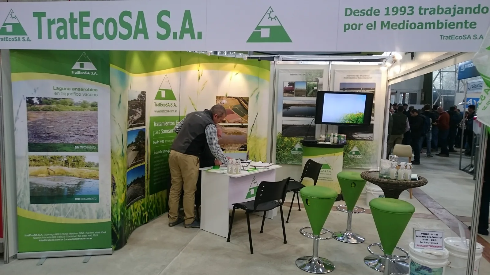 Stand de TratEcoSA S.A. en una feria del sector, con paneles que muestran el antes y el después del tratamiento de una laguna anaeróbica en un frigorífico vacuno